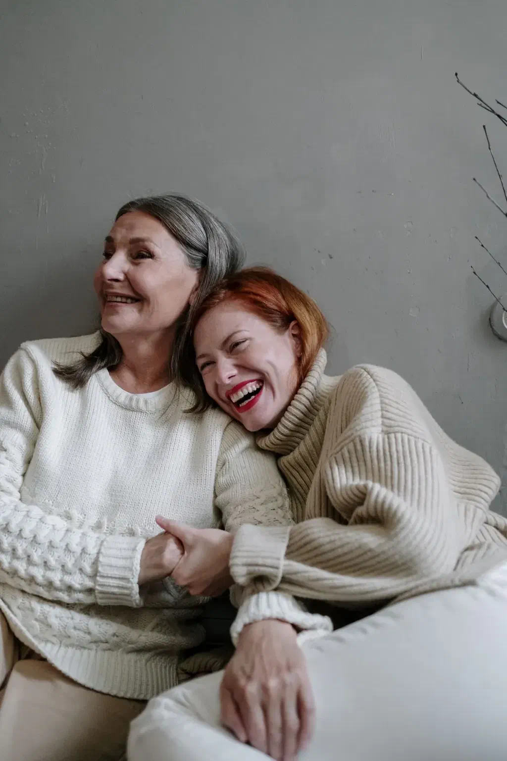 Une femme âgée et sa fille rient ensemble, blotties l'une contre l'autre